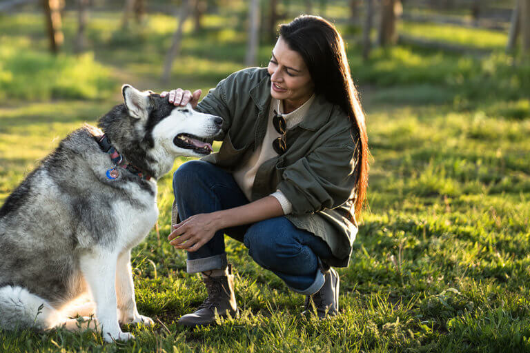 A woman playing with her big dog outside in her Breckenridge boots