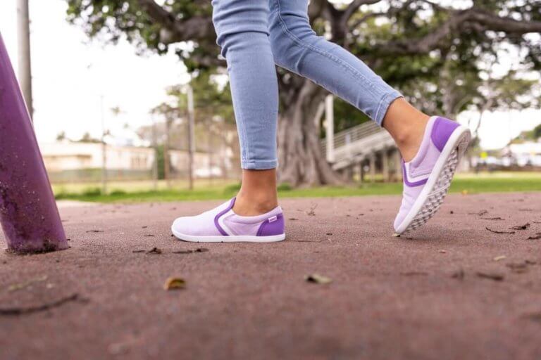 A girl walking around a sports field in her Dillon Canvas Slip-On Youth shoes