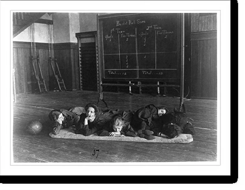 Historic Framed Print, [Five girls lying on mat in gymnasium in front of basketball scoreboard, Western High School, Washington, D.C.], 17-7/8
